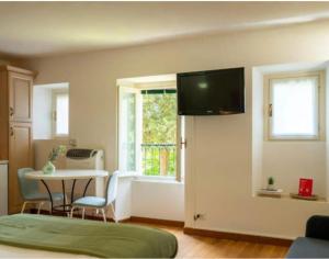 a living room with a table and a television on a wall at Tiny Apartment on the Lake in Tremezzo