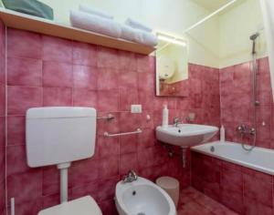 a red bathroom with a toilet and a sink at Tiny Apartment on the Lake in Tremezzo