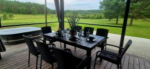a table and chairs on a deck with a large window at Sodyba Azagis in Vilkanastrai +15 photos