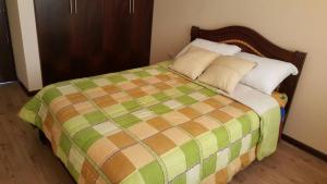 a bedroom with a bed with a green and brown blanket at Casa Vacacional in Cuenca