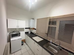 a white kitchen with a sink and a microwave at The Dharma Lodge in Enfield