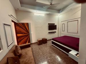 a bedroom with a purple bed and a tv at Harmony House in Ghaziabad