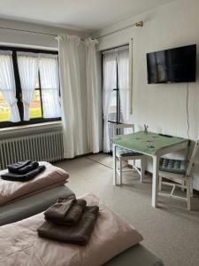 a room with two beds and a table and a television at Casa pasa - Idylle mit Bergblick in Inzell