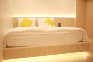a large bed with white sheets and yellow pillows at Kim Poshtel Hatyai in Hat Yai