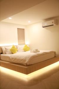 a bedroom with a large white bed with yellow pillows at Kim Poshtel Hatyai in Hat Yai