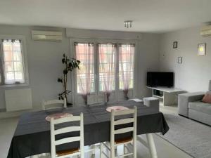 a living room with a dining room table and chairs at Maison 2 chambre, salon, 5 couchage 57 rue du drain 95480 Pierrelaye in Pierrelaye