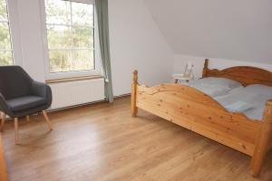a bedroom with a wooden bed and a chair at Ferienwohnung in Möllenhagen