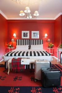a large bed in a red room with two suitcases at Areela Boutique Hotel in Tirana