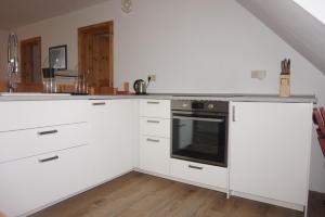 a kitchen with white cabinets and an oven at Ferienwohnung in Möllenhagen