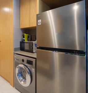 a stainless steel refrigerator in a kitchen with a washing machine at Golden Sunset Luxe 1BR CB2-3-RA1-812-1br in Sabkhah