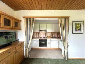 a small kitchen with white cabinets and a television at Chalet Cristall Superior Appartement 1 in Leutasch