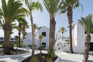 a row of palm trees in front of a white building at BLUESEA Playa Club in Puerto del Carmen