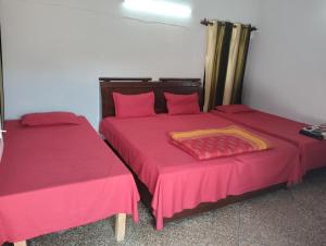two beds in a room with red sheets and curtains at Thakur Shri Dwarkadhish Seva Sadan in Mathura
