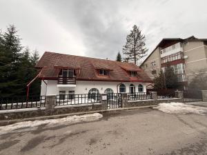 a white house with a red roof and a building at Shiro Nord Rooms in Predeal