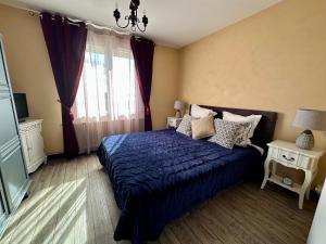 a bedroom with a blue bed and a window at l'ANNEXE in Verdigny
