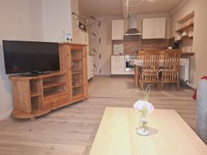 a living room with a television and a vase of flowers on a table at Ferienwohnung Naeve - helle, gemütliche Wohnung auf dem Lande mit zwei Schlafzimmern in Barderup +11 photos