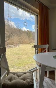 a living room with a large window with a table and chair at Domek Ranczo Podkówka "przed" Bieszczady in Lipa