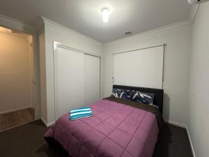 ein Schlafzimmer mit einem lila Bett mit einer lila Decke in der Unterkunft Your Guest House in Tarneit