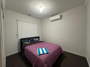 ein Schlafzimmer mit einem Bett mit einer lila Decke in der Unterkunft Your Guest House in Tarneit