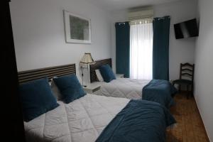 a bedroom with two beds with blue pillows at Residencial Miguel José in Estremoz