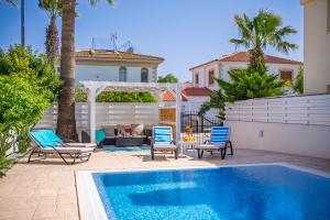 a swimming pool with two chairs and a house at Palm Villa Eva in Paralimni