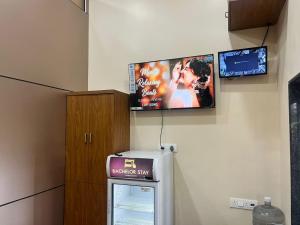a flat screen tv on a wall with a refrigerator at Bachelor Stay - CBD Belapur in Navi Mumbai +5 photos