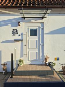 a white door on a house with a wooden porch at Pension Fiete Celle in Celle