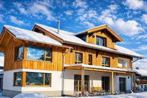 a wooden house with snow on the roof at Landhaus Sonnenwang in Pfronten