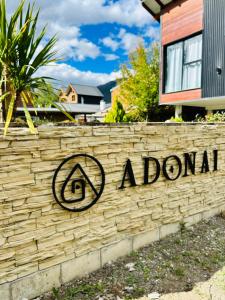 aonga sign on a brick wall in front of a house at Adonai, departamentos in El Bolsón