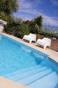 two white chairs sitting next to a swimming pool at Adonai, departamentos in El Bolsón