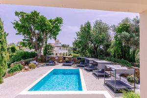 a swimming pool with chairs and a house at Casa do Alto in Vilamoura