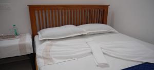 a bed with two white pillows and a wooden headboard at Smile Residency in Sultan Bathery