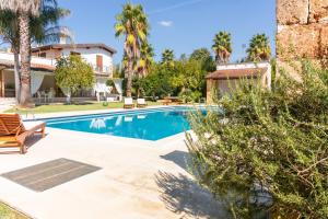 a swimming pool in front of a house with palm trees at Villa Padula in Sogliano Cavour