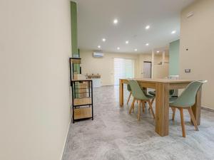 a dining room with a wooden table and green chairs at ToNo House in Paterno
