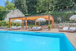 a swimming pool with chairs and a gazebo at Appartamento Splendore in Bellagio