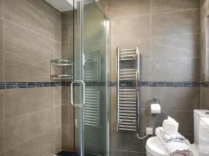 a bathroom with a glass shower with a toilet at Pandy Cottage in Aberdyfi +20 photos