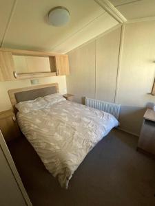 a bedroom with a bed with a white comforter at Cleethorpes Beach Haven - Broadland Drive in Cleethorpes +11 photos