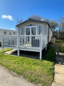 a white house with a porch and a white fence at Cleethorpes Beach Haven - Broadland Drive in Cleethorpes