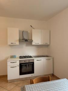 a kitchen with a stove and white cabinets and a bed at Casa Speranza in Narzole