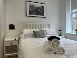 a bedroom with a white bed with towels on it at Stylish 2 Bedroom Coastal Apartment near Crosby Beach & Liverpool in Waterloo