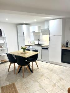 a kitchen with white cabinets and a wooden table and chairs at La Maisonnette Champenoise in Villers-sous-Châtillon