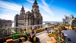 people sitting on a balcony in front of a building at Stylish 2 Bedroom Coastal Apartment near Crosby Beach & Liverpool in Waterloo