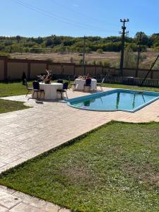 a swimming pool with tables and chairs in a yard at Casa Ioanele in Valea Perilor