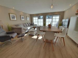 a living room with a couch and a table and chairs at Hues-Sylt in Morsum