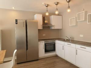 a kitchen with a stainless steel refrigerator and white cabinets at Hues-Sylt in Morsum +4 photos