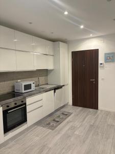a kitchen with white cabinets and a brown door at Lake Agno Apartment in Agno
