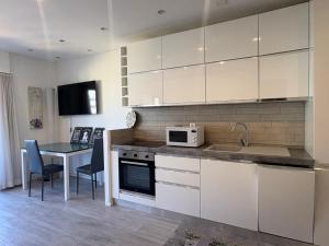a kitchen with white cabinets and a table with a microwave at Lake Agno Apartment in Agno