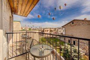 a balcony with a table and chairs and hot air balloons at Pegas Goreme in Göreme