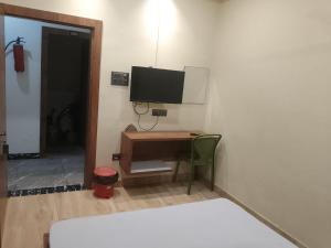 a room with a desk with a television on a wall at M D Guest House in Guwahati