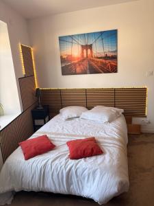 a bedroom with a bed with two red pillows on it at Studio charleureux et cosy in Sceaux-dʼanjou